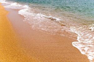 fermer, calme océan ou mer le surf s'écraser sur une d'or sablonneux plage photo