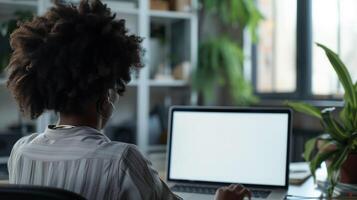 ai généré plus de épaule coup de une femme d'affaires en utilisant ordinateur portable dans de face de un Vide blanc ordinateur écran dans Bureau photo