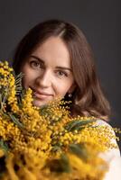 portrait de une fille avec une bouquet de mimosa, printemps humeur, de la mère journée photo