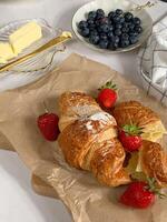 des croissants avec Frais baies et beurre sur une blanc Contexte. photo