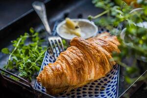 croissant avec beurre et Frais herbes sur une foncé Contexte. photo