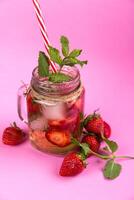 rafraîchissant été boisson avec des fraises et menthe dans une pot sur une rose Contexte photo