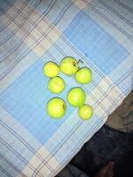 une groupe de vert pommes séance sur une bleu et blanc à carreaux table tissu photo