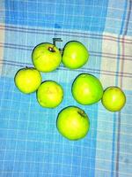 une groupe de vert pommes séance sur une bleu et blanc à carreaux table tissu photo