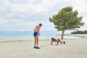 Jeune musclé homme exercice sur le plage, Jeune musclé homme Faire musculation des exercices sur le plage, athlétique Jeune homme sur le plage photo