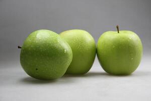 une empiler de Trois vert pommes sur blanc Contexte photo