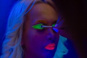 portrait de une femme avec peint affronter, femme avec uv maquillage dans studio, portrait de une femme dans carnaval masque, le femme est décoré dans une ultra-violet poudre photo