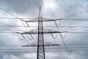 grand électricité pylônes dans détail en dessous de orageux ciels photo