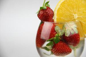une verre de l'eau avec des fraises et un Orange tranche photo