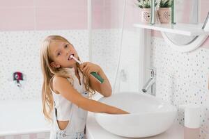 mignonne fille brosses sa les dents dans le salle de bains hygiène concept photo
