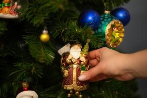 mains décorer Noël arbre avec élégant babiole dans atmosphérique de fête chambre. joyeux Noël. hiver vacances préparation photo