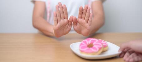 femme main rejeter Donut dessert, femelle refuser mauvais pour la santé déchet aliments. suivre un régime contrôle, poids perte, obésité, en mangeant mode de vie et nutrition concepts photo