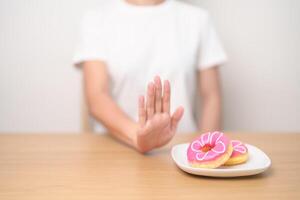 femme main rejeter Donut dessert, femelle refuser mauvais pour la santé déchet aliments. suivre un régime contrôle, poids perte, obésité, en mangeant mode de vie et nutrition concepts photo