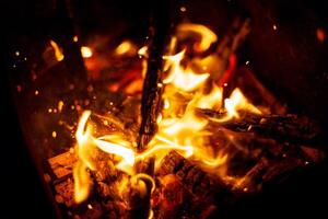 Feu avec charbons des brûlures dans le nuit. en bois journaux sont brûlant. photo