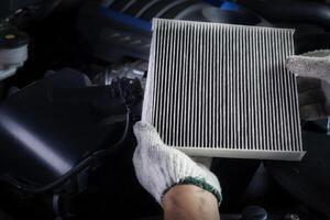 voiture air Conditionneur système entretien, main mécanicien en portant voiture air filtre à vérifier pour nettoyer sale ou réparer réparation chaleur avoir une problème ou remplacer Nouveau ou changement filtre. photo