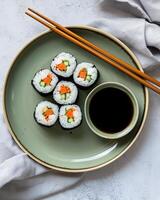 ai généré futomaki Sushi sur une vert assiette avec Shoyuu dans une petit bol, là sont deux baguettes et une chiffon, le table utilisé est brillant ciment photo