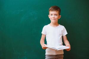 retour à école concept. école enfant dans classe. content enfant contre vert tableau noir. intelligent enfant dans Salle de classe. idée et éducation concept photo