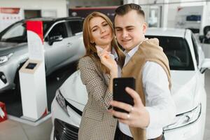 famille selfie dans concession. content Jeune couple choisit et achat une Nouveau voiture pour le famille photo