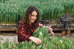 magnifique Jeune souriant fille, ouvrier avec fleurs dans serre. concept travail dans le serre, fleurs. photo