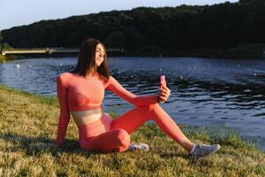 Jeune caucasien femme Faire actif formation exercice sur une yoga tapis près le rivière dans été. concept de en bonne santé mode de vie photo