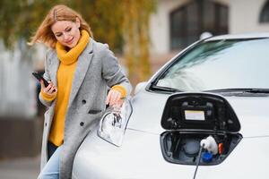 femme près une de location électrique auto. véhicule accusé à le mise en charge gare. photo