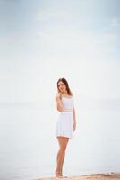 magnifique femme dans une blanc robe en marchant sur le plage.détendu femme respiration Frais aérien, émotionnel sensuel femme près le mer, profiter été.voyage et vacances. liberté et inspiration concept photo