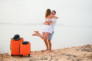 Jeune couple avec valise sur le plage dans été journée. le concept de des loisirs à mer et Voyage photo