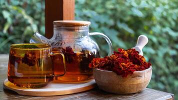 souci fleur en bonne santé thé dans verre agresser avec thé pot sur jardin tableau. à base de plantes médicament délicieux tisane thé avec Frais Jaune fleur pissenlit fleurs thé Coupe. vert clairière infusion fleurs sauvages éco amical durable en mangeant photo