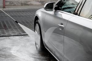 la lessive luxe argent voiture sur sans contact voiture laver. la lessive sedan voiture avec mousse en libre service et haute pression l'eau. nettoyage le détails de auto. propreté et commande dans Urbain environnement photo