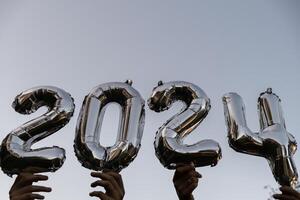 argent déjouer nombre 2024 fête Nouveau année ballon sur bleu ciel Contexte. content Nouveau année salutations concept. mains en portant des ballons deux mille vingt-quatrième année Noël vacances concept photo