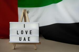 message texte je l'amour Émirats arabes unis sur Contexte de agitant Émirats arabes unis drapeau fabriqué de soie. uni arabe émirats drapeau avec concept de tourisme et en voyageant. attrayant salutation carte, publicité. Dubai accueillant carte photo