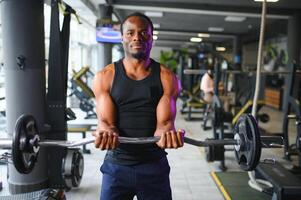 portrait de athlétique homme avec haltère dans mains exercice à Gym photo