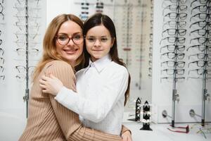 magnifique peu fille dans optique boutique ensemble avec maman choisir Nouveau lunettes. photo
