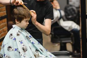 de bonne humeur caucasien garçon avoir coiffure dans salon de coiffure. photo