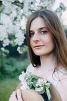 magnifique Jeune fille dans blanc robe et chapeau dans épanouissement Pomme verger. épanouissement Pomme des arbres avec blanc fleurs. photo