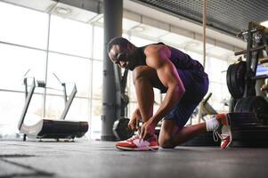 africain homme attacher les lacets à baskets dans le Gym photo