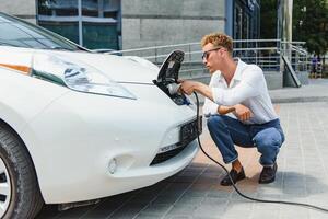 souriant homme débrancher le chargeur de le voiture photo