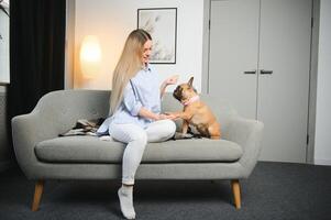 magnifique roux femme séance sur une canapé en riant et câlins une chien photo