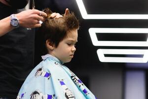 de bonne humeur caucasien garçon avoir coiffure dans salon de coiffure photo