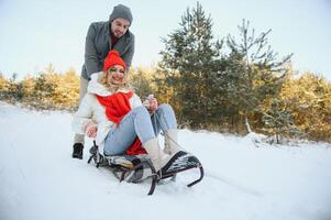 Jeune content couple luge dans hiver à forêt photo