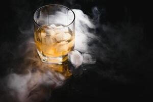 whisky avec la glace sur noir Contexte avec fumée photo