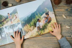le main enfant en portant une famille photo album contre le Contexte de le une en bois table