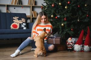 magnifique fille séance sur le canapé avec une chien sur le Contexte de Noël photo