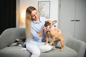 Jeune jolie femme dans décontractée vêtements étreindre sa chien séance sur le canapé dans le vivant pièce de sa confortable pays maison. animal la communication concept photo