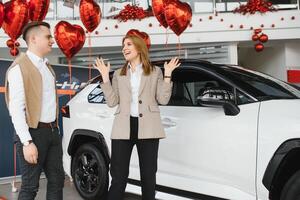 Jeune couple en utilisant une voiture dans une voiture salle d'exposition. photo