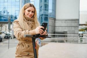 Jeune femme sur électro scooter dans ville. femme équitation scooter dans le coucher du soleil lumière dans rue photo