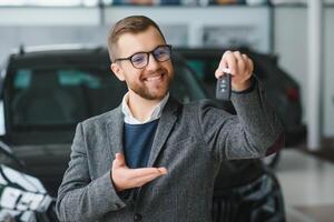 bien en regardant, de bonne humeur et amical vendeur pose dans une voiture salon ou salle d'exposition. photo