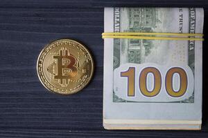d'or bitcoin et dollars dans Masculin main sur une foncé bleu en bois Contexte. or pièce de monnaie de crypto-monnaie. photo