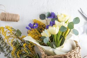 printemps bouquet de fleurs. Iris, tulipes, mimosa et eucalyptus. Jaune et bleu fleur. bourgeon fermer. floral Contexte. violet iris, blanc double tulipe. Mars ambiance. photo