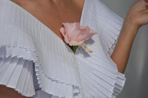 fille la mariée dans une blanc robe avec une rose Rose fleur dans sa encolure. photo